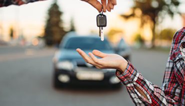 Male driving teacher gives the keys to female student after exam, successful end of car school concept. Test for drivers, automobile course